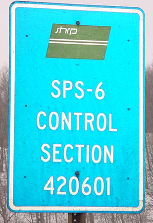 A close-up of a sign from the LTPP program's SPS-6 experiment. The sign has the SHRP logo at the top. The text on the sign reads "SPS-6 Control Section 420601."