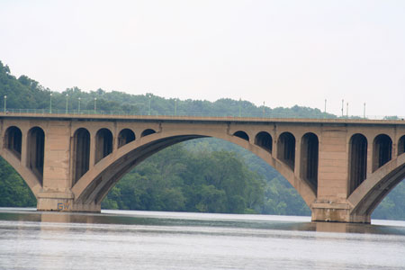A side view of an arched bridge spanning a river.
