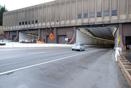 A view of the entrance to the Eisenhower/Johnson Memorial Tunnel on I-70 in Colorado. A car is entering the tunnel.