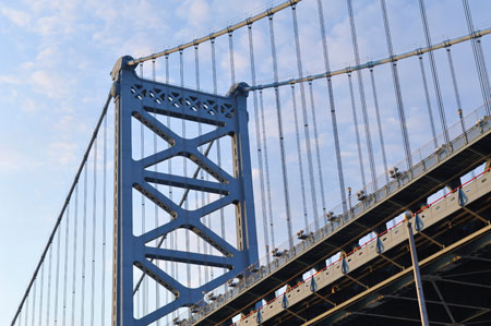 A side view looking up at a steel suspension bridge.