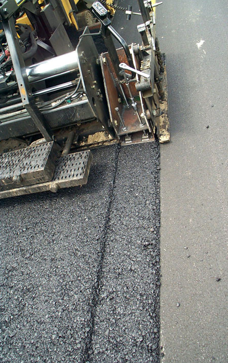 A close-up view of an asphalt paver laying down asphalt.