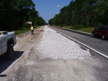 A view of a lane on M-115 in Clare County, Michigan, after it has been rubblized. A roadway worker is visible on the side of the road.