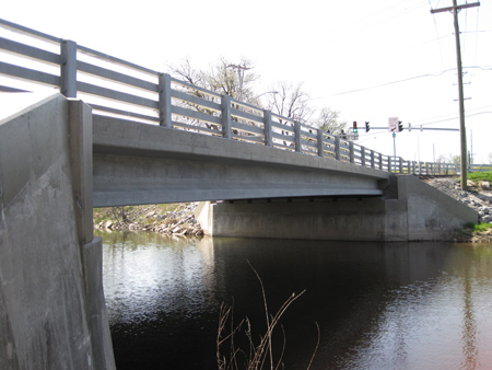 A side view of the single-span Route 31 bridge in Lyons, NY. The bridge crosses a waterway. Field-cast ultra-high performance concrete connections were used to construct the bridge.