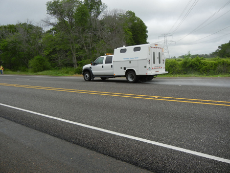A side view of FHWA's Highway Friction Tester traveling down an empty roadway.