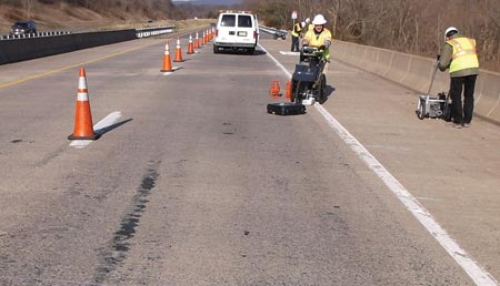 In this image, an NDE assessment team is working on the Virginia steel multigirder cluster bridge on Rt. 7 over South Fork of the Catoctin Creek. The team is working on the far-right lane of the highway, which has been blocked off from traffic with orange cones.