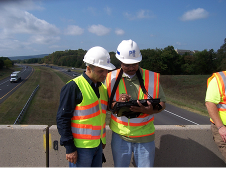 Figure 3. FHWA LTBP Program Manager Hamid Ghasemi (left) and an infrastructural expert examine plans on site.