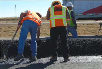 Figure 3. Photograph of field crew measuring the temperature of the dropped asphalt concrete for the New Mexico SPS-10 site.