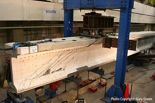 A picture showing shear testing of a 54-inch deep, LWHPC prestressed girder in the Structural Testing Laboratory at the Turner-Fairbank Highway Research Center. It displays cracking on the girder. (Photo Copyright: Gary Greene.)