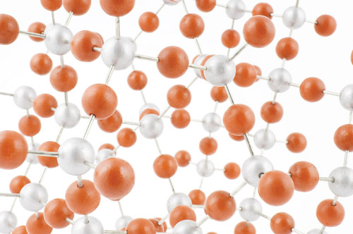 Closeup of a model of a molecule, composed of small, red- and silver-colored spheres intercconnected using short metal pins.