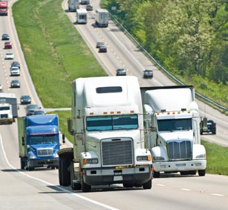 Three trucks in close formation are pictured ascending a hill. 