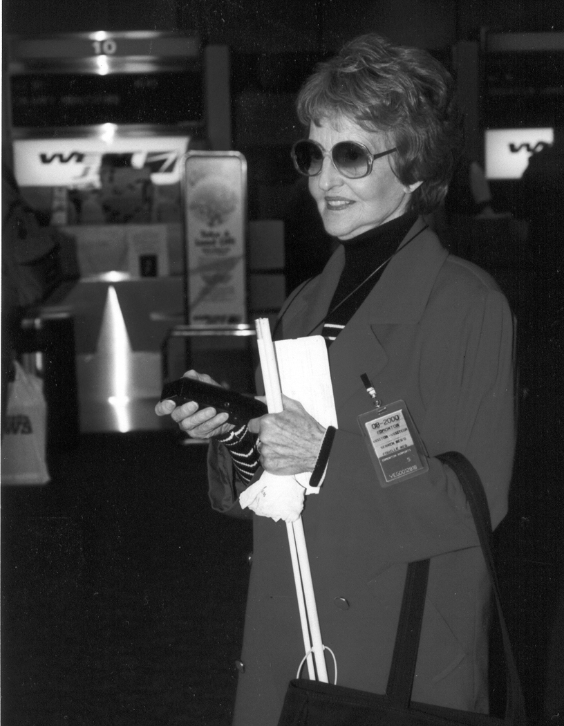Figure 9. Photo. A visually-impaired traveler with a cane is shown using a handheld wayfinding device at a transit station.