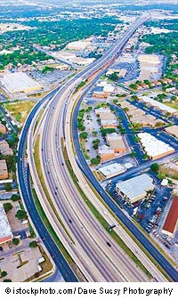 A birds-eye view of a multilane highway running through an urban corridor.