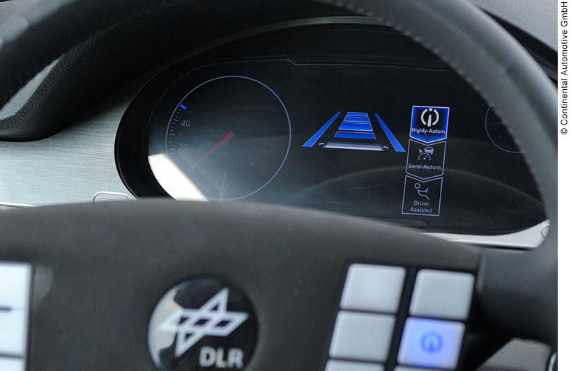 View of a digital car dashboard through a steering wheel. On the left side of the dashboard is a speedometer that only goes up to 40 km/hr; the current speed is zero. To the right of the speedometer is digital display of the driver-vehicle interface (DVI) for this car. The DVI mode icons are “Driver Assisted” (a stick figure in a driving position), “Semi-Automated” (a car and a speedometer with an arrow pointing at the speedometer), and Highly-Automated” (the HAVEit logo).  The Highly Automated icon is currently lit in blue, indicating that it is active.