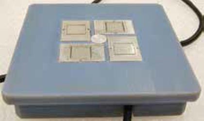 A blue-gray, thin, rectangular plate with attached wiring. A pressure sensor and four other metal pieces are embedded on the plate’s surface.