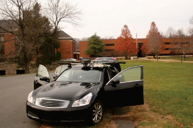 A research vehicle with equipment mounted on the roof is pictured in front of the Turner-Fairbank Highway Research Center.