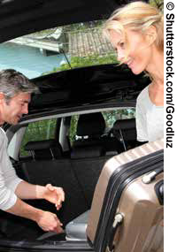 Man and woman packing suitcases in vehicle.