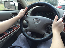 Photo of a pair of hands on a steering wheel.