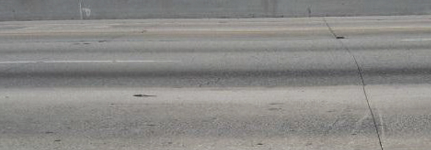 Photo of Interstate 10 near Los Angeles, also called the San Bernardino Freeway. The roadway surface shows wear and damage, including joint deficiencies and spalls.