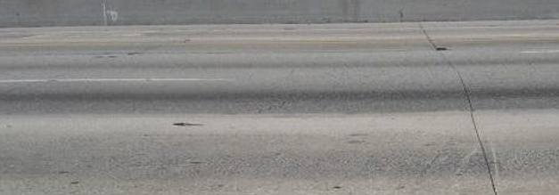 Photo of Interstate 10 near Los Angeles, also called the San Bernardino Freeway. The roadway surface shows wear and damage, including joint deficiencies and spalls.