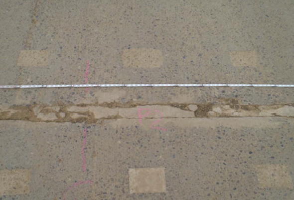 Close-up photo of a section of the Dalton Highway in Alaska. There appears to be some cracking in the roadway, which has been patched with magnesium phosphate grout. The highway is otherwise in good condition after 20 years of use.