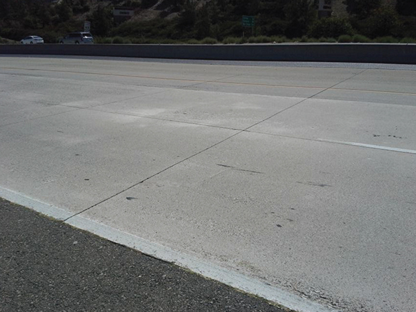 Photo of the Route 60E/71N interchange near Los Angeles. The roadway does not have any traffic on it and the roadway surface appears to be in good condition after 17 years of use.  