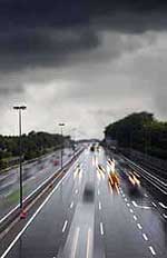Photograph. Vehicles travel down a wet highway in both directions.