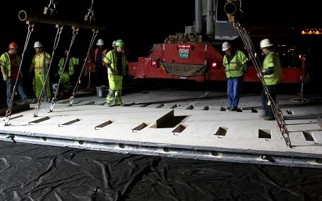 A stock photo shows several workers inspecting a precast, prestressed concrete panel.