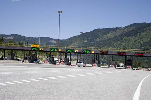Stock photo shows toll booths stretching across a multi-lane highway. Digital signs over the booths read "Open" and "Closed."