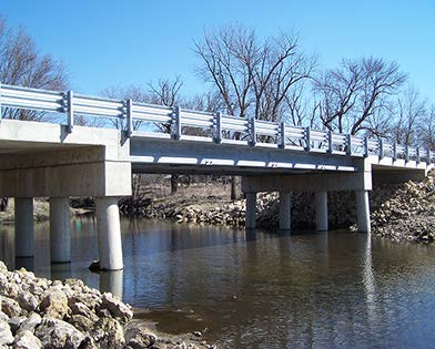 Stock photo shows a bridge with ultra-high performance concrete pi-girders extending over a small stream or river.