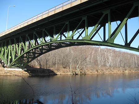 Stock photo shows an arch bridge extending over a small stream or river.