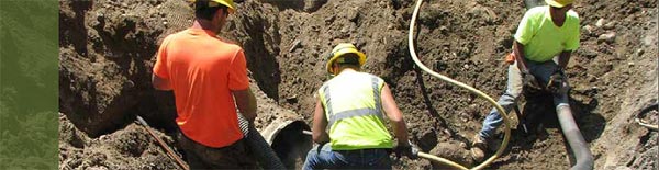 This figure illustrates workers use a high-pressure jet wash and truck-mounted vacuum to remove debris from existing pipes as part of preparations for the FHWA supported culvert reconstruction project conducted by Montana DOT using trenchless technologies. Half of the corrugated steel pipe culverts would be lined (sliplined) with high-density polyethylene pipe and half would be lined with cured-in-place pipe. (Image source: FHWA)