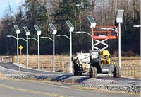 This figure shows solar-powered lamps installed along a pedestrian walkway in proximity to a busy highway. (Image source: FHWA)