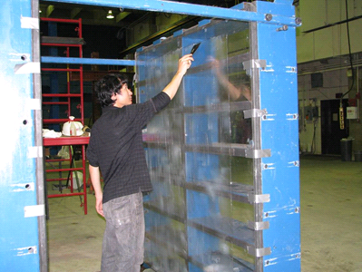 This photo shows a worker applying a lubricating agent to the inside surface of Plexiglas® that has been taped to the inside of the test bin.