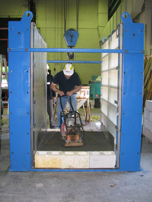 This photo shows a worker using a hand compactor to compact the first layer of backfill, creating a smooth surface.