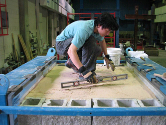 This photo shows a worker crouching on top of the composite mass and using a level to complete the process of compaction.