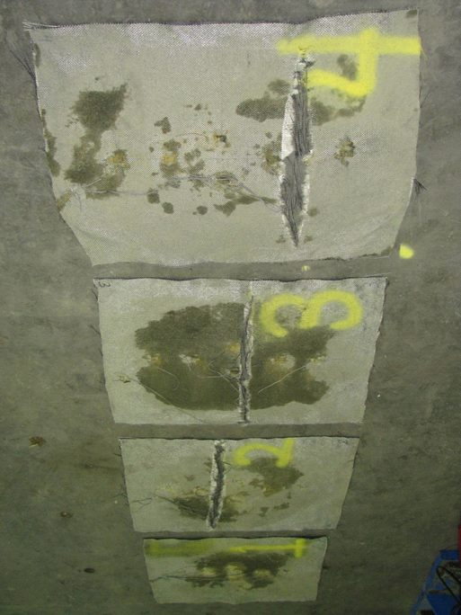 This photo shows all four of the geosynthetic reinforcement layers from the test 3 composite mass. Sheets 1 through 4 are shown, with sheet 4 at the top and sheet 1 at the bottom. Clear rupture lines can be seen, which highlight the location of maximum strain.This photo shows all four of the geosynthetic reinforcement layers from the test 3 composite mass. Sheets 1 through 4 are shown, with sheet 4 at the top and sheet 1 at the bottom. Clear rupture lines can be seen, which highlight the location of maximum strain.