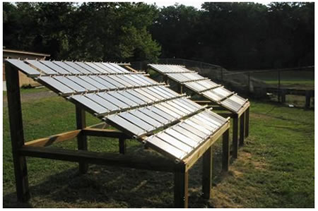 Figure 7. Photo. Mild NW exposure rack at TFHRC. This photo shows mild natural weathering (NW) exposure racks at Turner-Fairbank Highway Research Center (TFHRC). The racks are similar in design and structure to those in figure 6, except that they are inclined at 30 degrees. These racks face south and have nonmetallic (Teflon®) hinges to support the test panels. Two racks are shown: one for NW with salt spray and the other for NW only. A solution of 15 weight percent sodium chloride was manually sprayed every 24 h onto these panels. 

