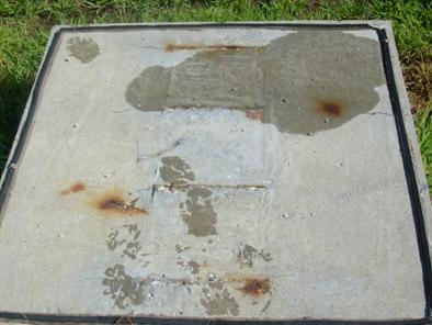 Corrosion products have caused cracking on the upper surface of the specimen. Corrosion products are near the surface at each simulated crack, and three large corrosion spots are visible away from the simulated cracks.