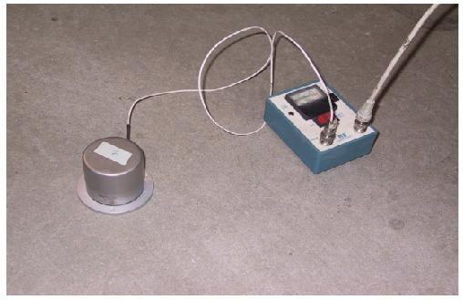 Seismic accelerometer and power supply unit. This image shows the PCB Piezotronics Model 393C seismic accelerometer that contains a built-in microelectronic amplifier that converts the high impedance voltage signals from the quartz crystals to a low impedance voltage. The accelerometer is connected to a power unit by a coaxial cable.