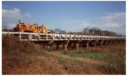 Relief structure 4 of the Trinity River Bridge with the Vibroseis truck over bent 2. This image shows relief structure 4 of the Trinity River Relief Bridge in the middle of the picture. On top of the bridge, at bent 2, is a Vibroseis truck, which is a large truck with a servo-hydraulic vibrator mounted on top.