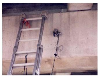 Biaxial accelerometer mount with vertical and horizontal accelerometers, west pier, Woodville Road Bridge. This image shows a biaxial accelerometer mount with vertical and horizontal seismic accelerometers installed on the beam cap of the west pier, Woodville Road Bridge. A ladder is leaning against the beam cap next to the mount.