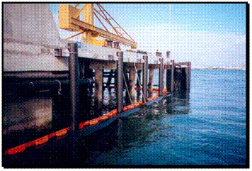 Figure 3. Photo. Fender piles in U.S. Naval Submarine Base, San Diego, California. This figure is a color photograph of a set of fender piles around the outside of an installation at the San Diego, California, U.S. Naval Submarine Base. The fender piles depict an example of one experimental use of fiber-reinforced polymer composite piles.