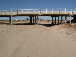 Figure 13. Mojave River, California. Photo. This figure shows a dry channel, looking toward a bridge. This can be considered to be a naturally unstable channel, primarily in the lateral direction, in that there is considerable lateral movement of the channel.
