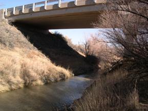 Figure 60. Rio San Jose, Trans Pecos-looking downstream at bridge. Photo. This is looking downstream at the bridge. Like figure 59, this photo shows a nearly trapezoidal section under the bridge.