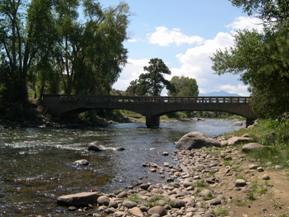 Figure 61. Arkansas River, Rocky Mountains-looking downstream at bridge. Photo. This is the Arkansas River in the southern Rocky Mountain region looking downstream at the bridge. The bed material is primarily gravel, and the bank vegetation is woody vegetation and annuals. 