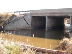 Figure 79. West Elk Creek, Central Plains-looking downstream at bridge, photo 2. Photo. Like figure 78, this photo looks downstream at the bridge. The photo shows a large displacement in the left wingwall and the water line crossing the stream just upstream of the bridge. 