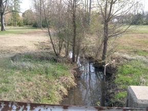 Figure 113. Unnamed creek (N 21), Ozark-Ouachita Highlands-downstream from bridge. Photo. This is unnamed creek N 21 in the Ozark-Ouachita Highlands region looking downstream from the bridge. Much of the vegetation on the banks has been removed. 