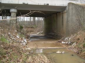 Figure 123. Unnamed creek (N 23), Atlantic Coastal Plain-looking downstream at bridge. Photo. This is looking downstream at the bridge. There is a concrete pad under the bridge and minimal bank stabilization riprap. 