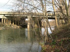 Figure 128. Unnamed creek (N 24), Atlantic Coastal Plain-looking downstream at bridge. Photo. This is looking downstream at the bridge. The channel is slightly narrower than it is further downstream, and no sediment deposition is apparent.