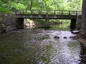 Figure 167. Aspetuck River, New England-looking upstream at bridge. Photo. This is looking upstream at the bridge. The channel is well-aligned with the bridge, but it is as wide as the bridge. The right bank is stabilized with a stone wall. 